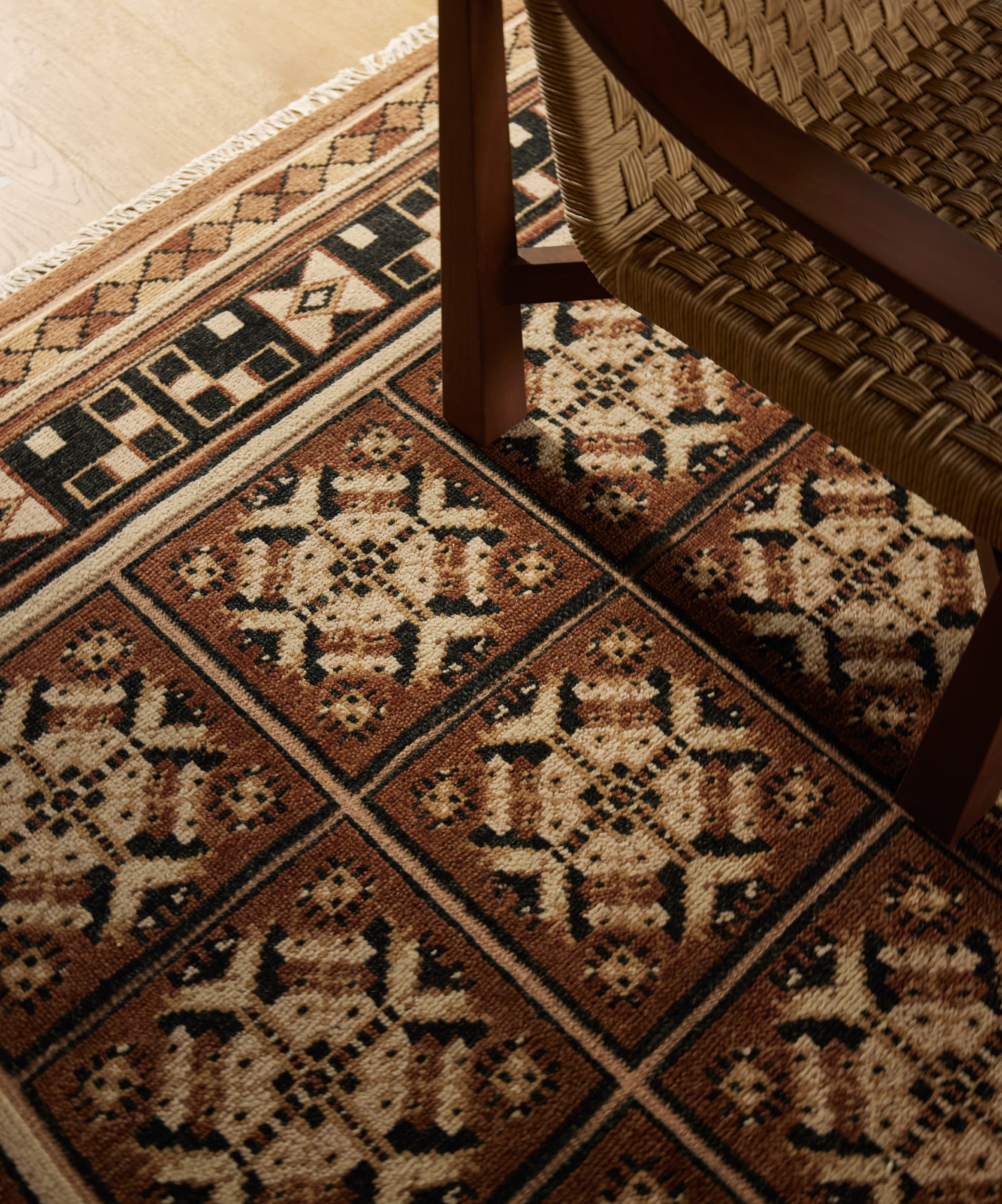 Close-up of a patterned floor tile with a corner of a wooden chair leg visible