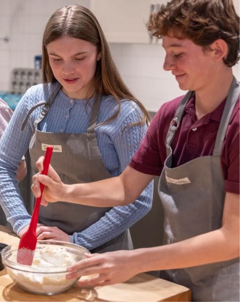 Teen girl and boy wearing aprons and cooking in Sur La Table summer series cooking class