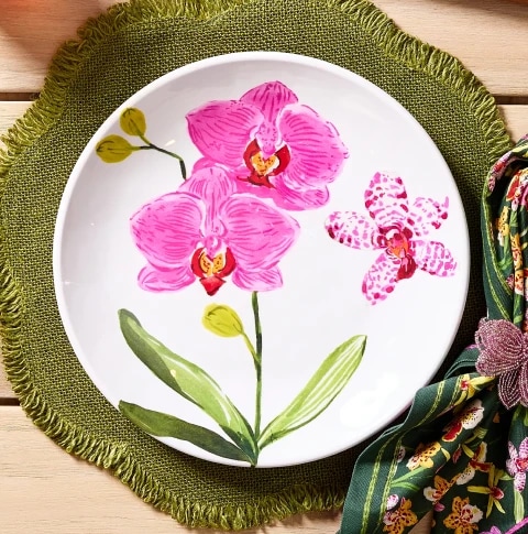 Decorative plate with pink orchids design, on a green ruffled placemat