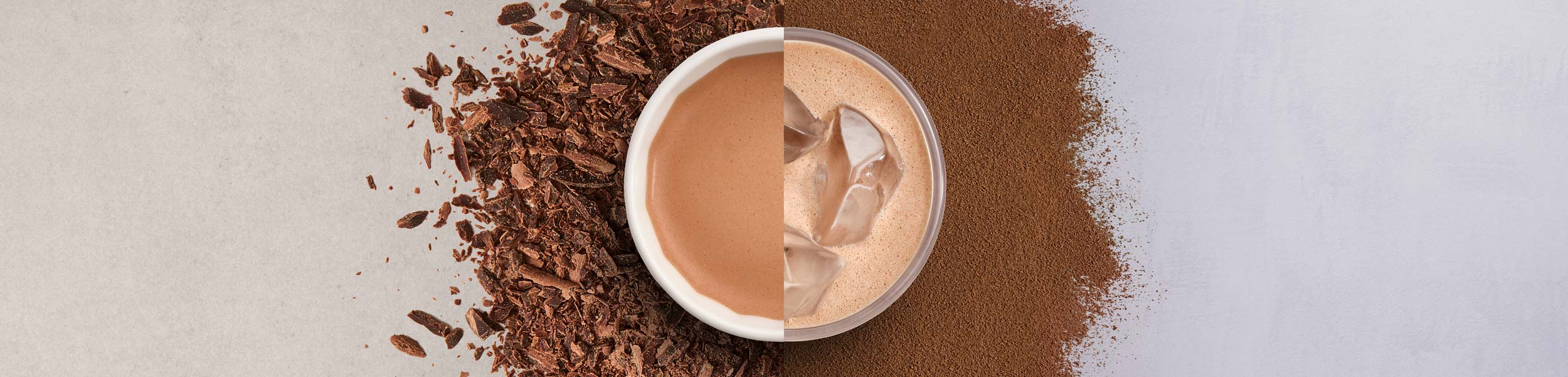 A cup of coffee with a foam art leaf design, surrounded by coffee grounds