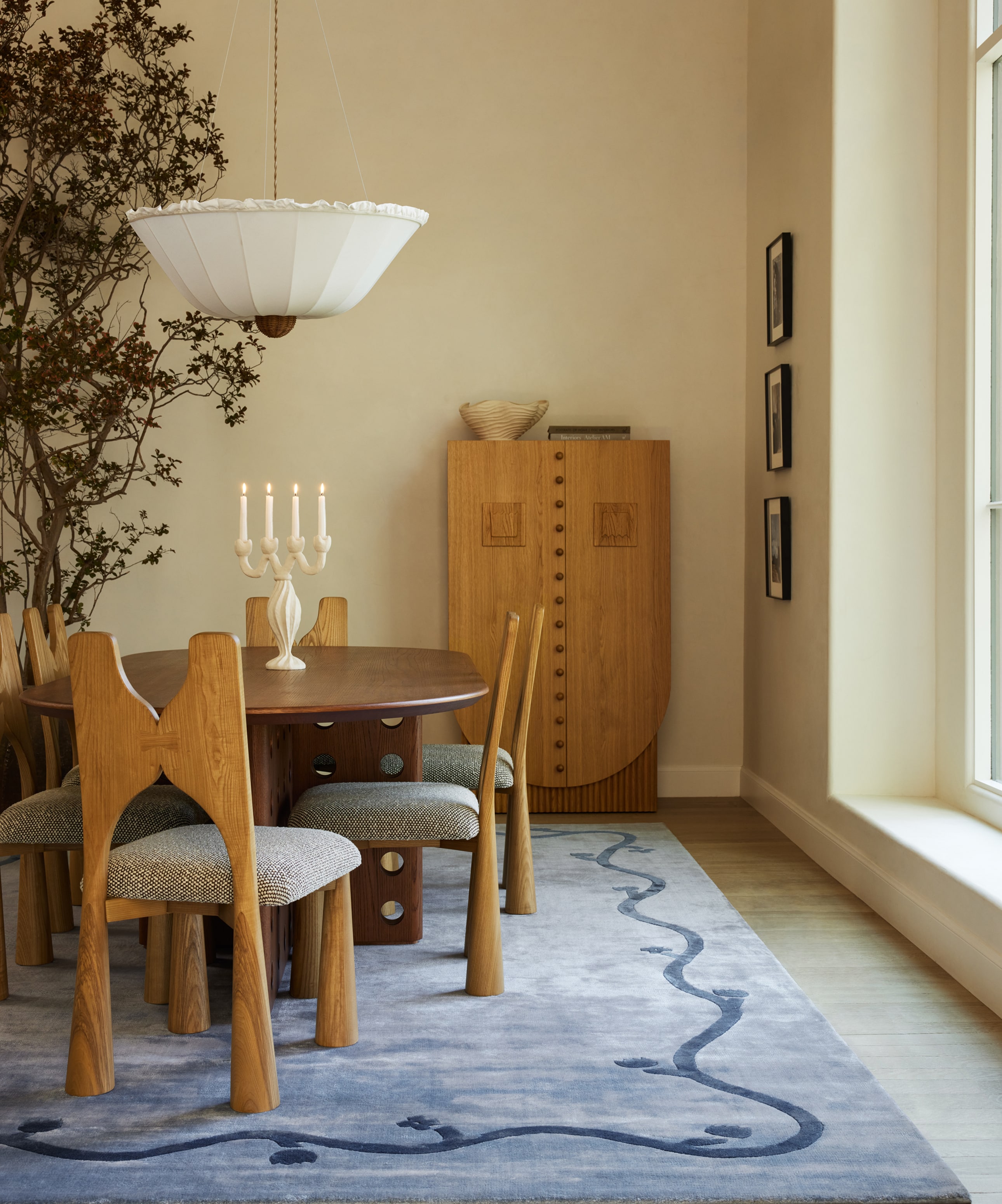 Cozy dining room with wooden table, chairs, unique cabinet, and artistic rug under soft lighting