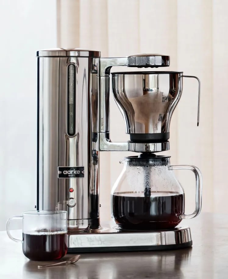 Modern coffee maker with a glass carafe against a softly lit background