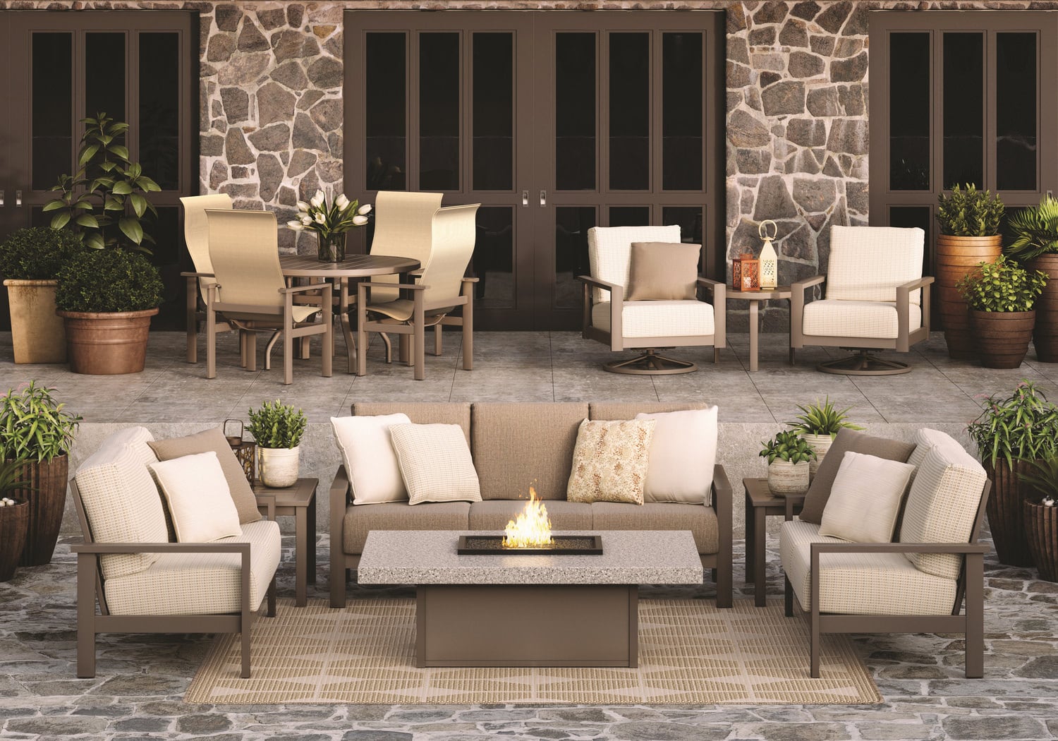 Outdoor furniture set with sofa and chairs on a patio in front of a stone wall