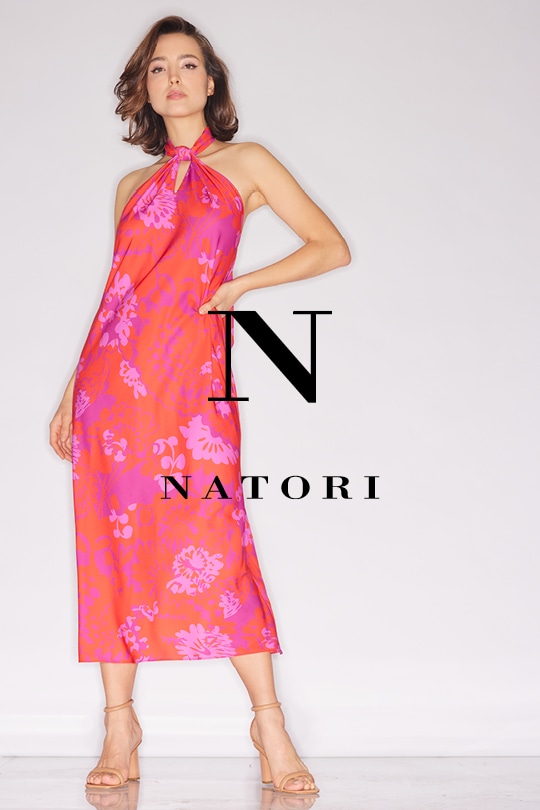 Woman posing in a pink floral halter dress with "Natori" logo