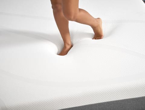 Child's bare foot stepping on a white foam mattress