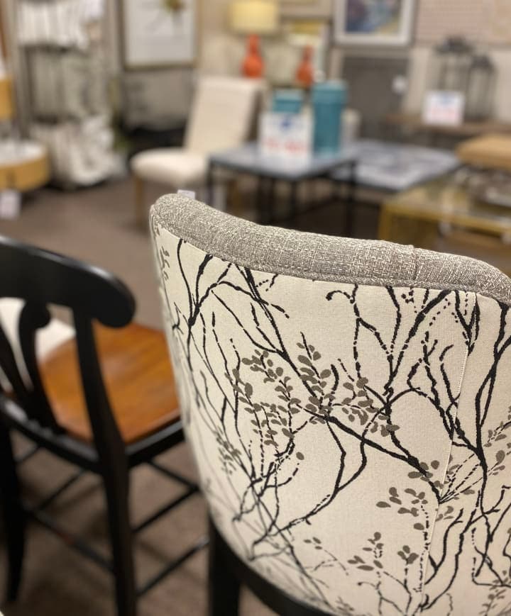 Close-up of a chair with botanical print upholstery in a blurred furniture store background