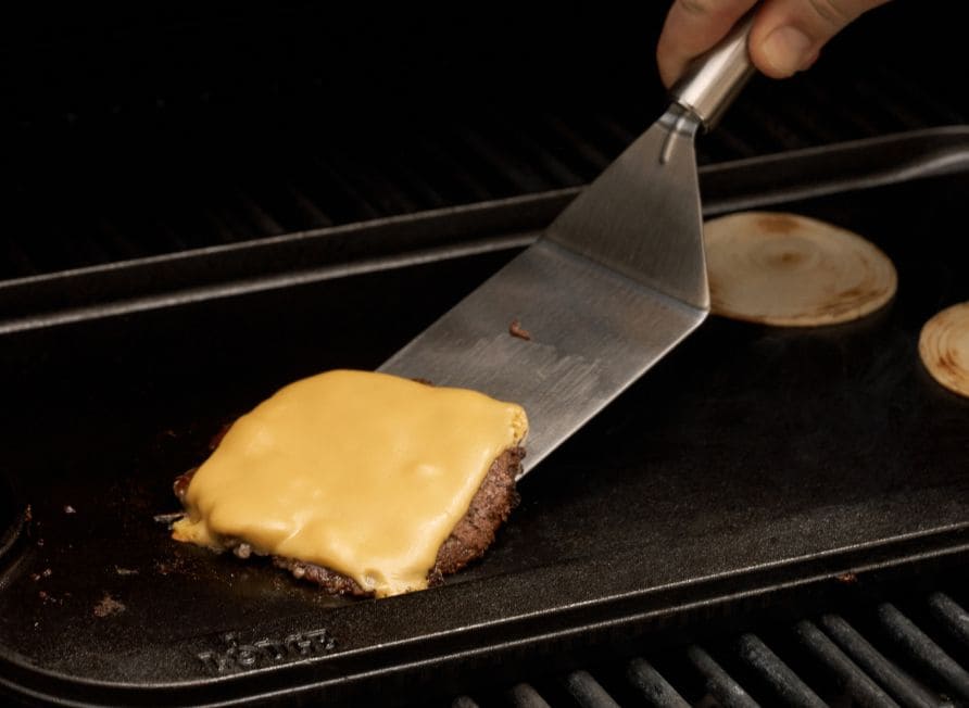 cheeseburger on cast iron griddle on outdoor grill
