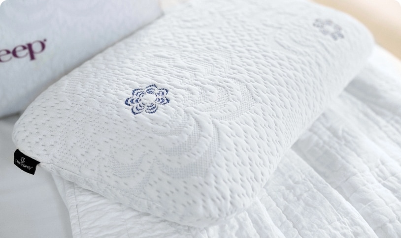White textured pillow with embroidered design on a bed