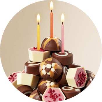 A collection of assorted chocolates with three lit candles