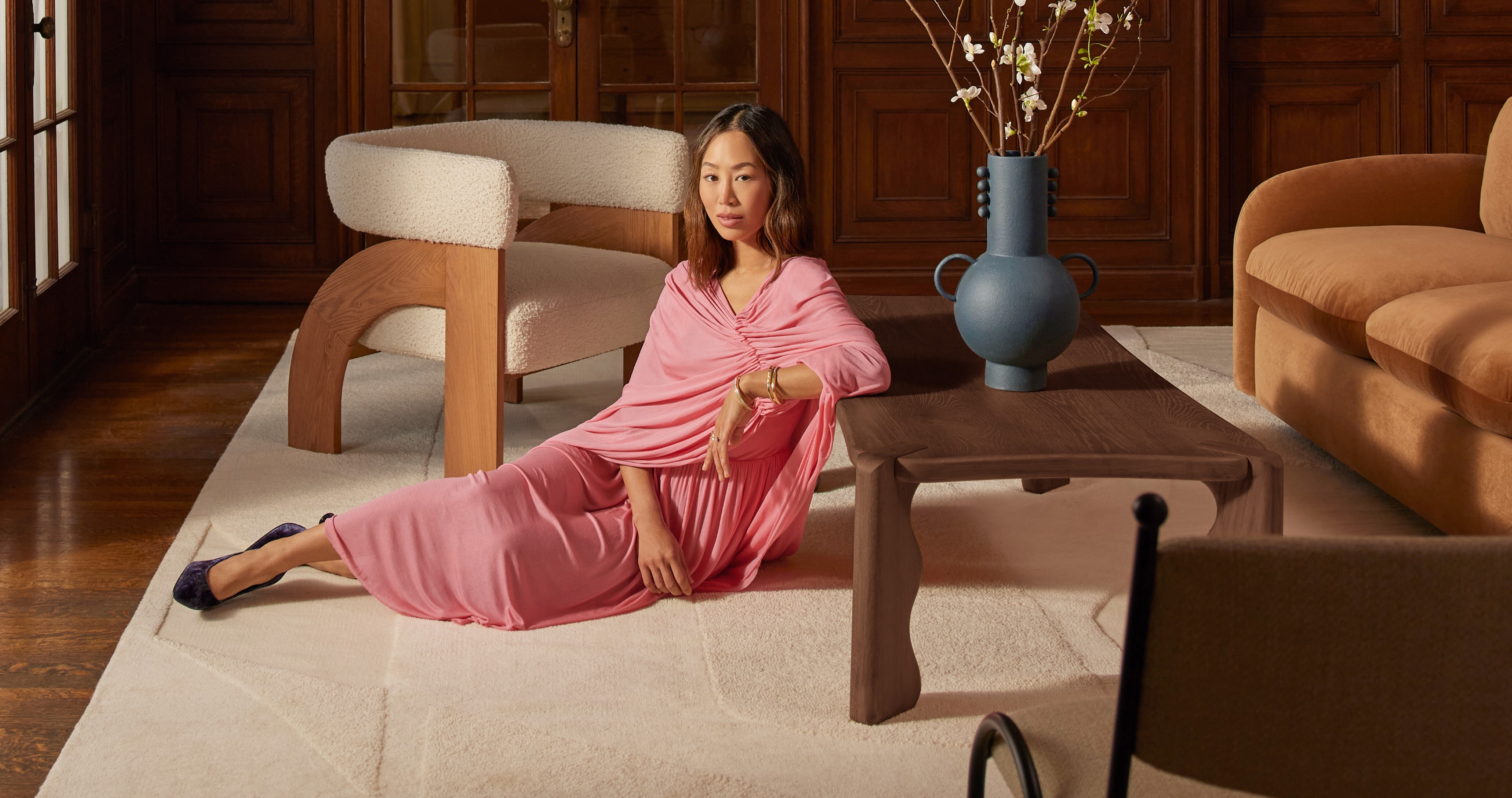 Woman in pink dress lounging in a stylish living room with modern furniture
