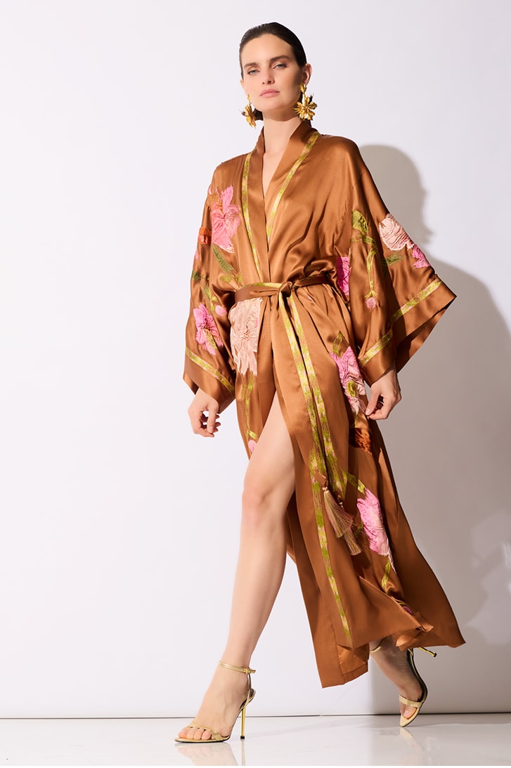 Woman posing in a gold floral kimono with beige heels against a white background