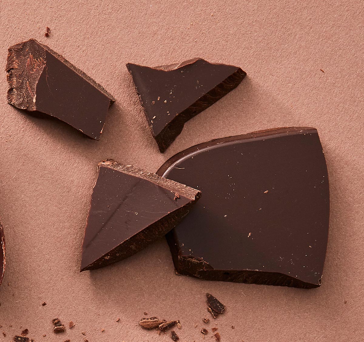 Broken pieces of dark chocolate on a textured surface