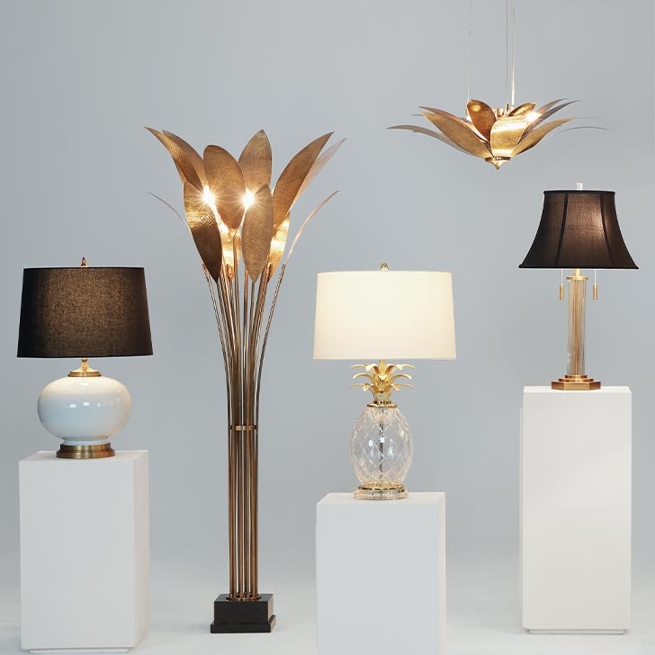 Variety of stylish lamps displayed on white pedestals against a gray background