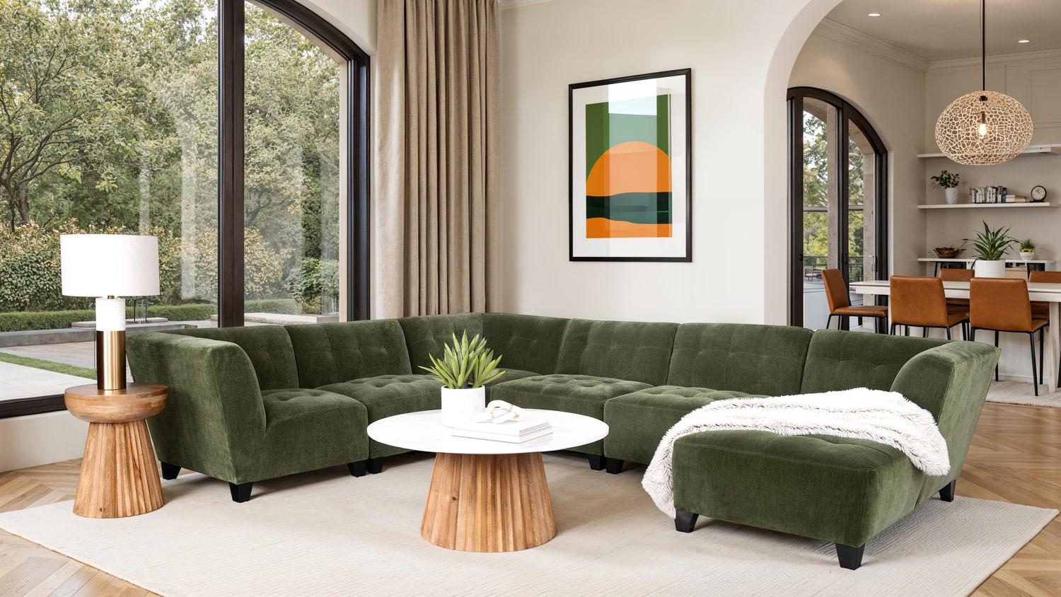 Elegant living room with a green sectional sofa, large windows, and modern decor