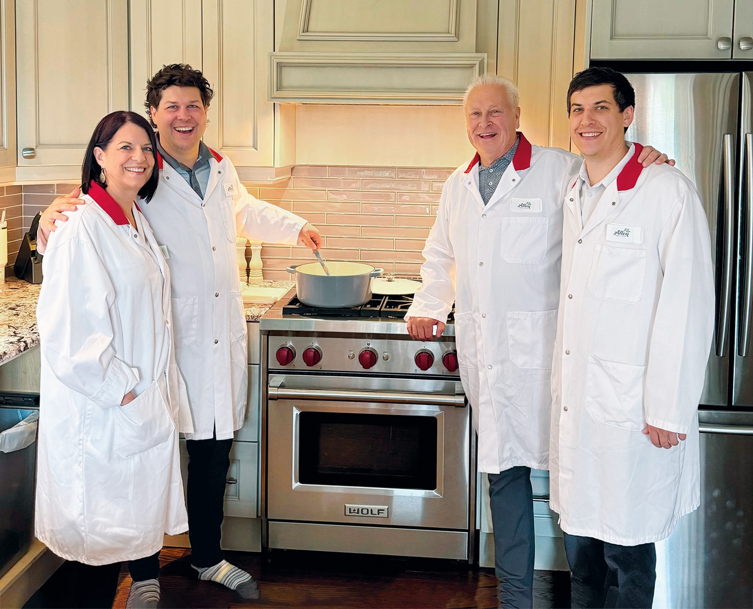 Quatre professionnels en blouses blanches souriants dans une cuisine