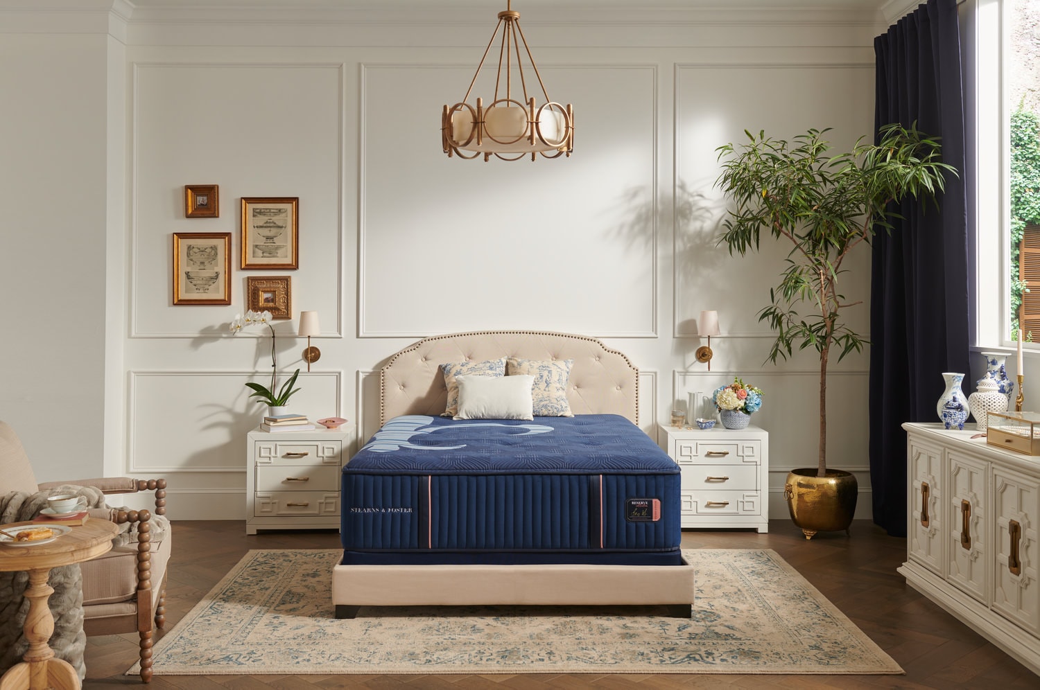 Elegant bedroom interior with a blue bed, white furniture, and decorative items