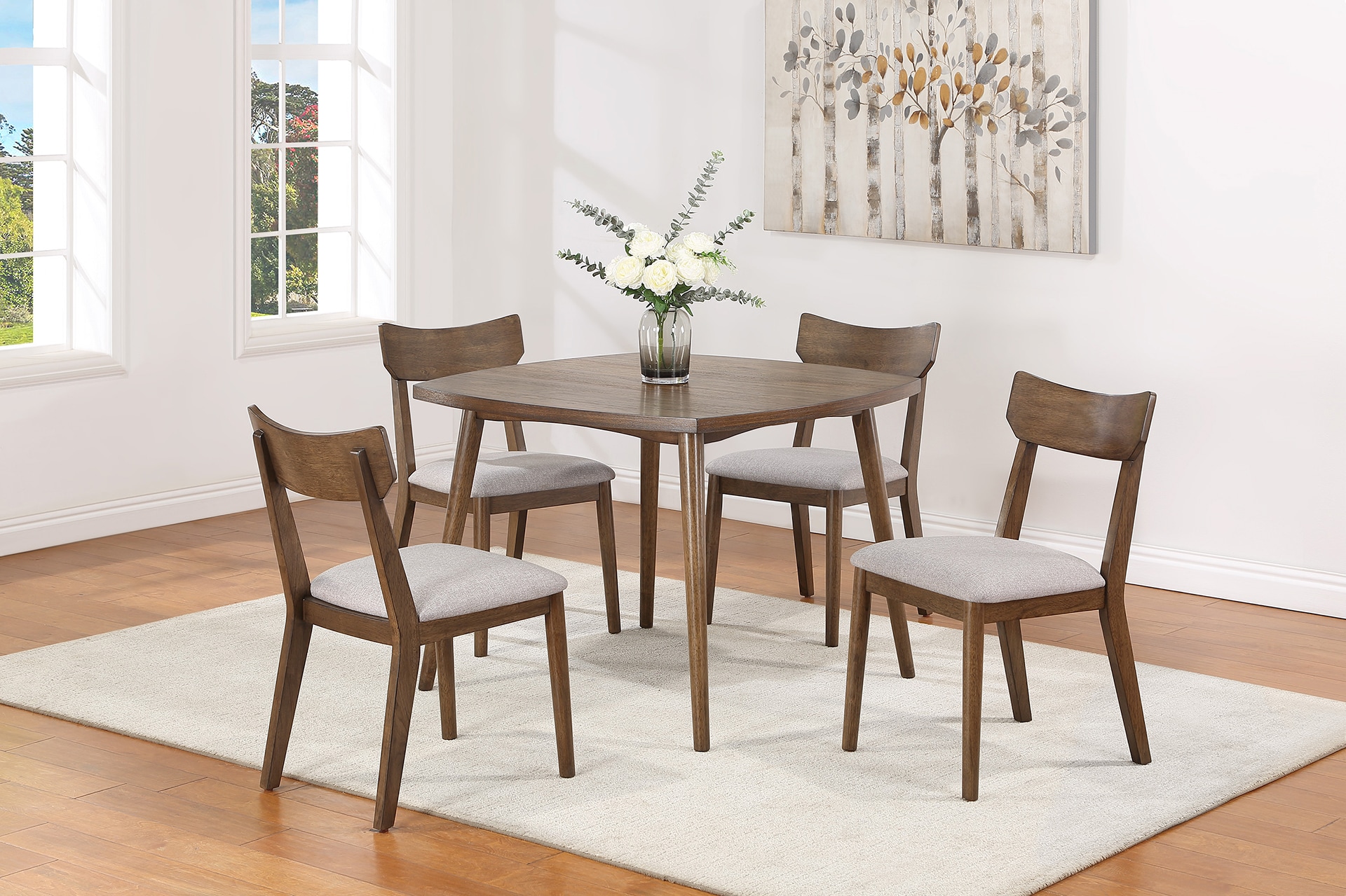 Modern dining room with a wooden table, four chairs, and a vase of flowers on a white rug