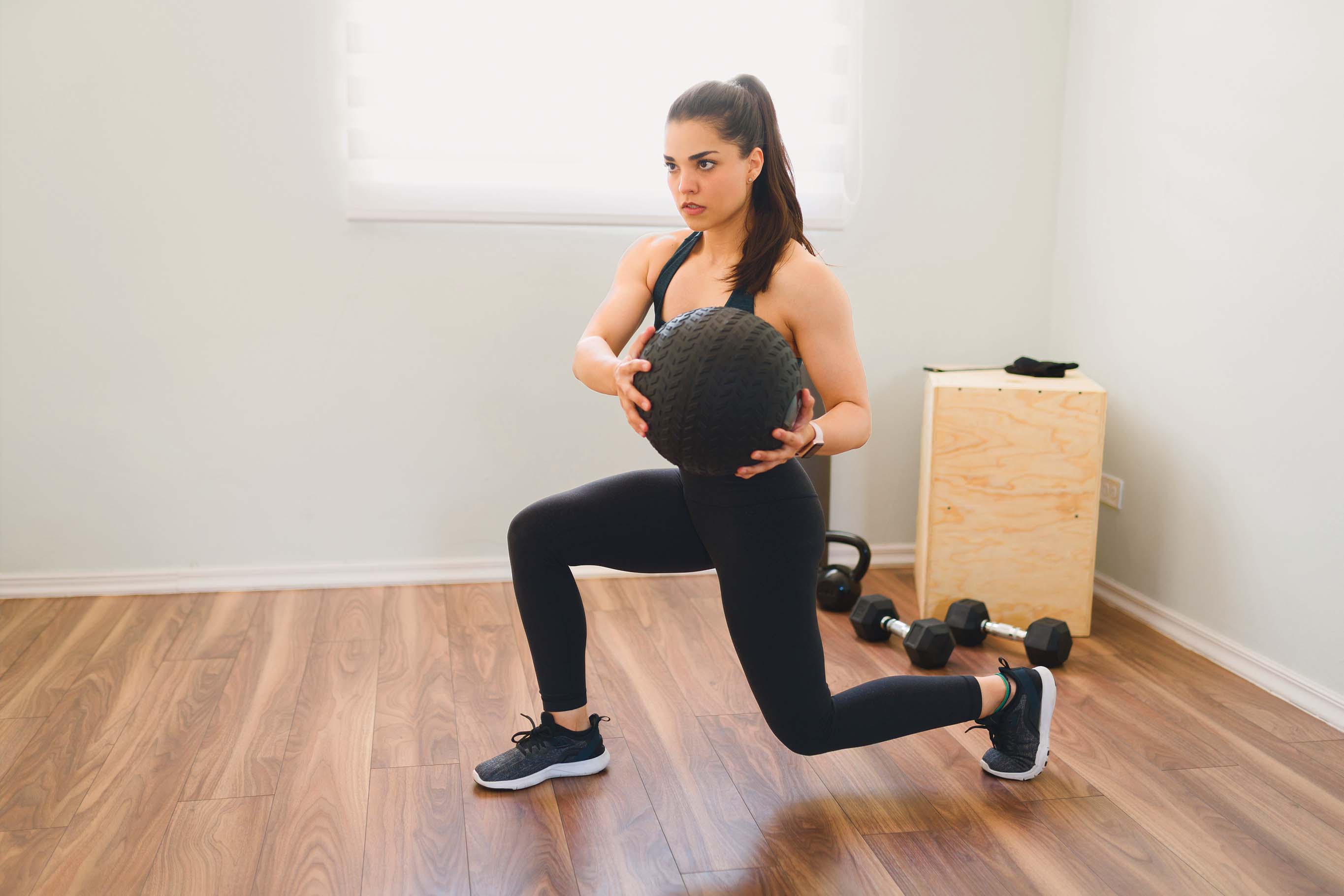 Femme faisant un exercice de fente avec un ballon de fitness dans une salle d'entraînement