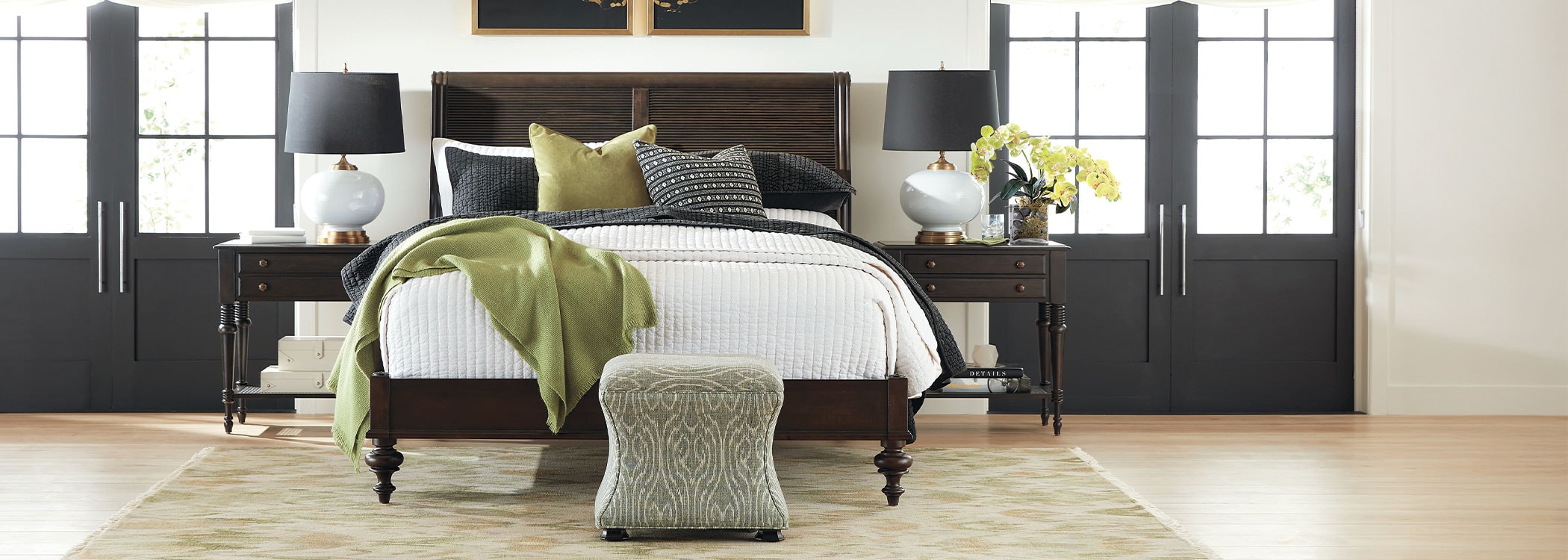 Modern bedroom with a large bed, green and white bedding, matching pillows, and dark framed artwork