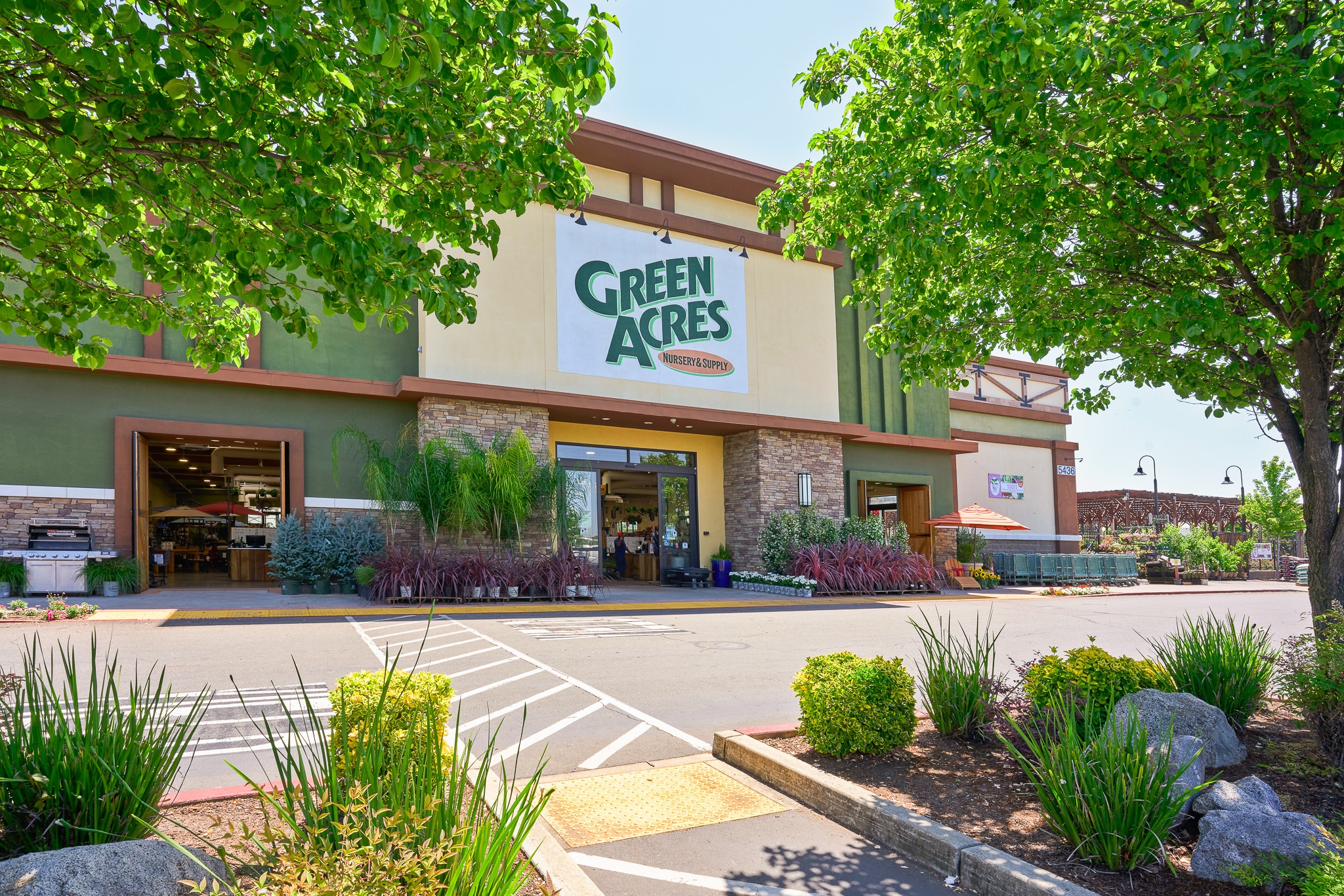 Exterior of Green Acres Market building with landscaped parking lot on a sunny day