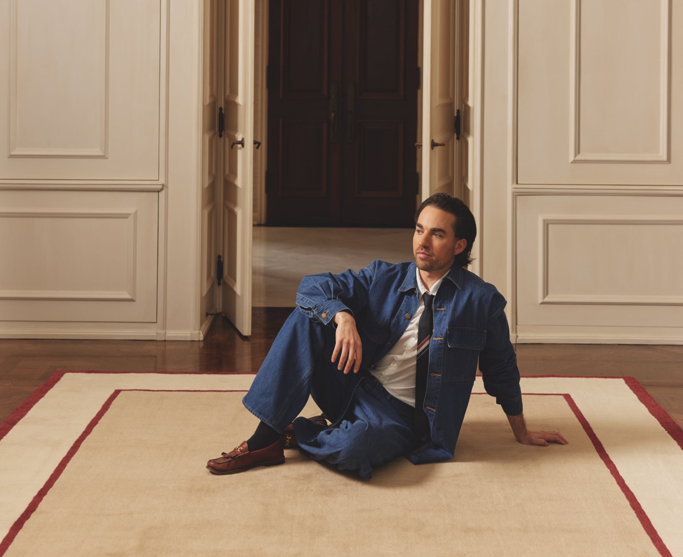 Man in blue suit sitting on floor by doorway