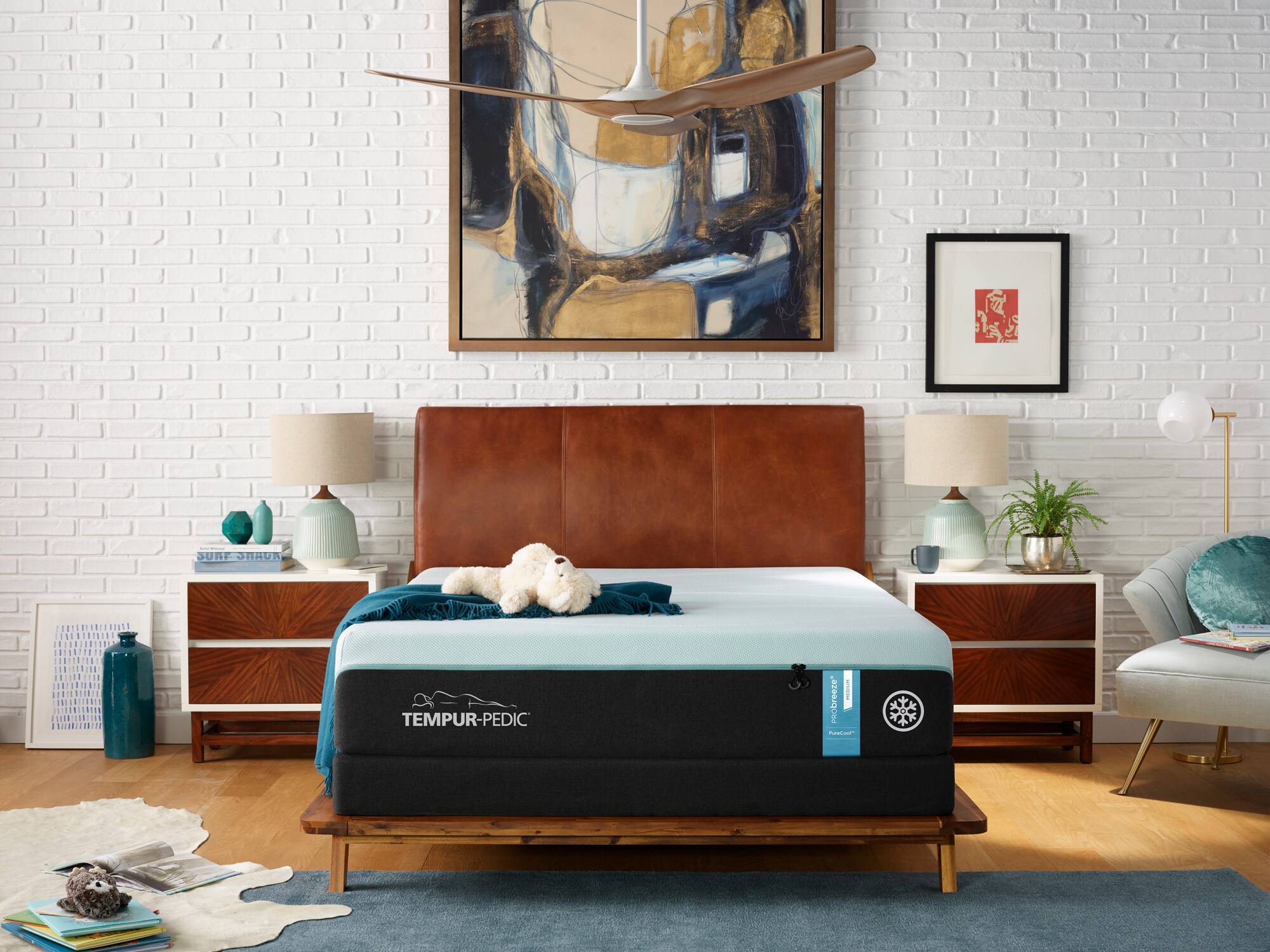 Modern bedroom with a Tempur-Pedic mattress, stylish furnishings, artwork, and a decorative brick wall